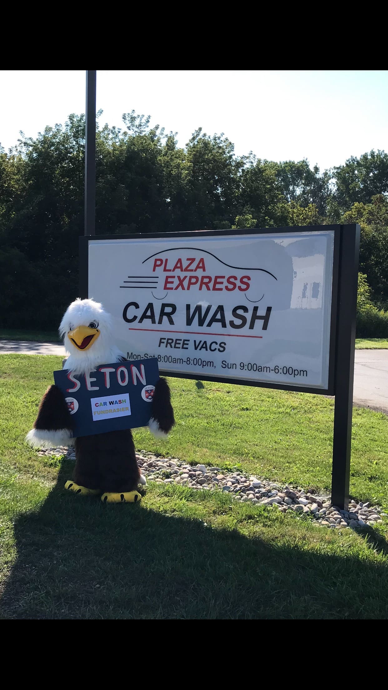 A person in costume holding up a sign for car wash.