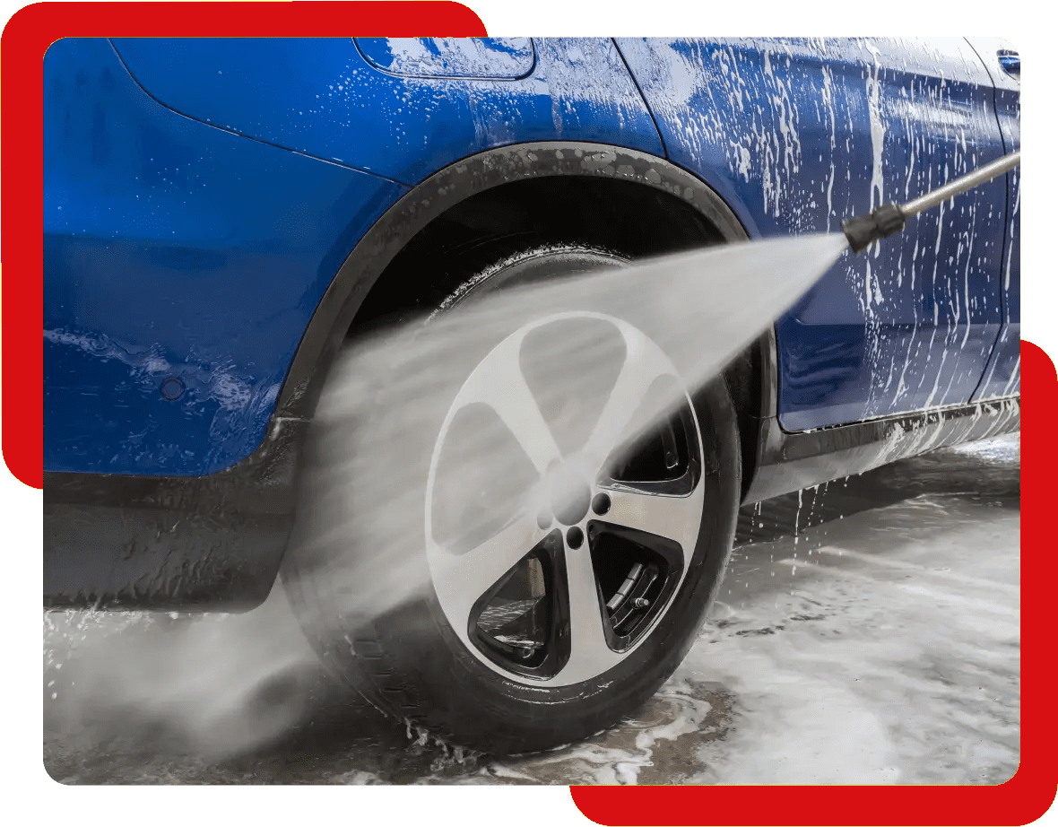 A car is being washed by a high pressure washer.