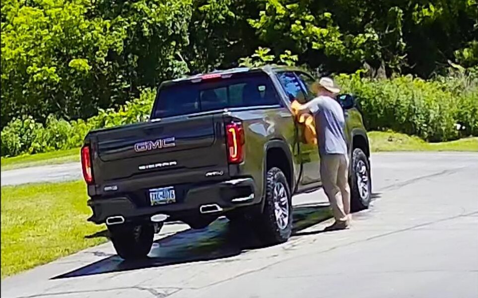 A man is standing next to the back of his truck.