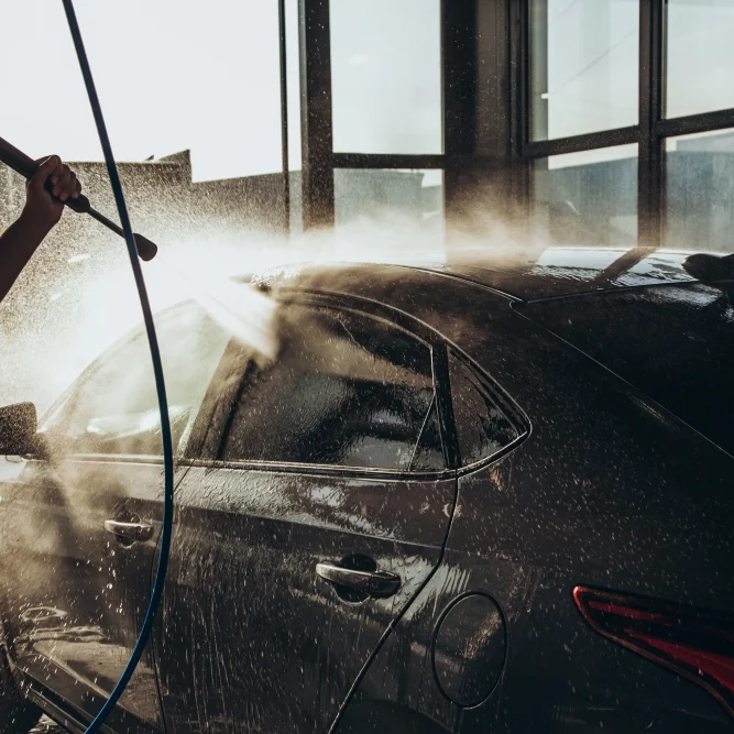 Person washing black car with a hose.